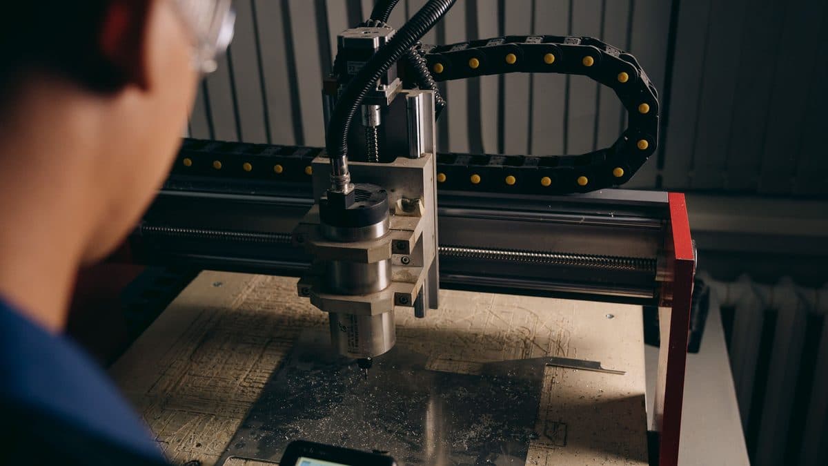 An operator watching a CNC machine cut a metal sheet